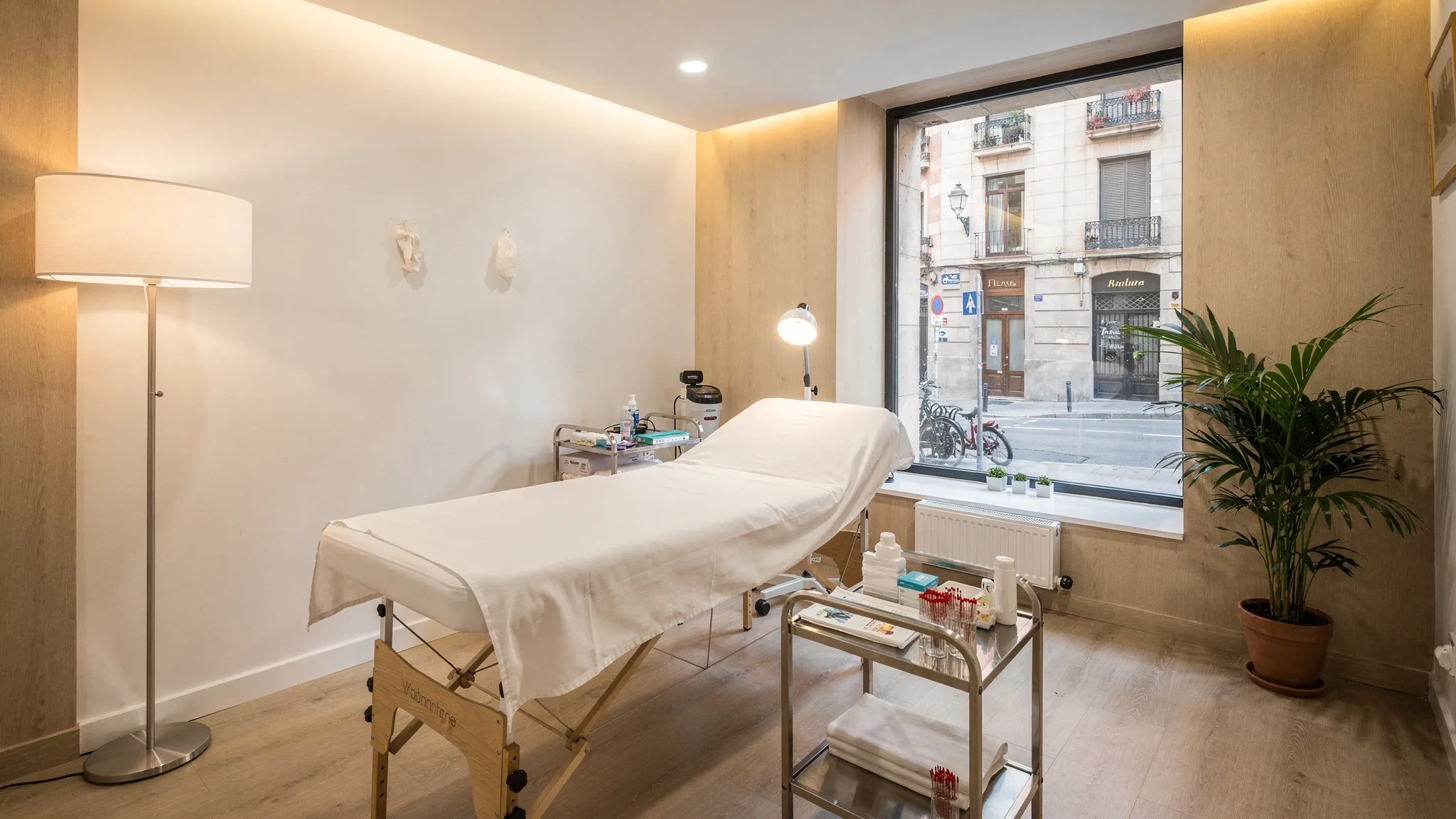Interior de una clínica de acupuntura en Barcelona con una camilla, luz cálida, materiales estériles preparados y un ambiente minimalista y relajante.