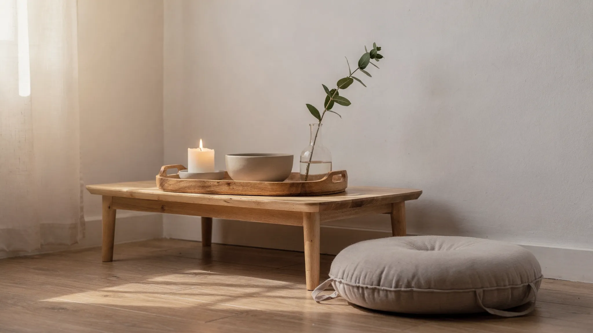 Un pequeño altar de meditación en una esquina luminosa del hogar: una bandeja de madera sobre una mesa baja, con una vela encendida, un cuenco sencillo, un pequeño jarrón con una rama verde y un cojín de meditación al lado. Ambiente cálido, minimalista y ordenado.