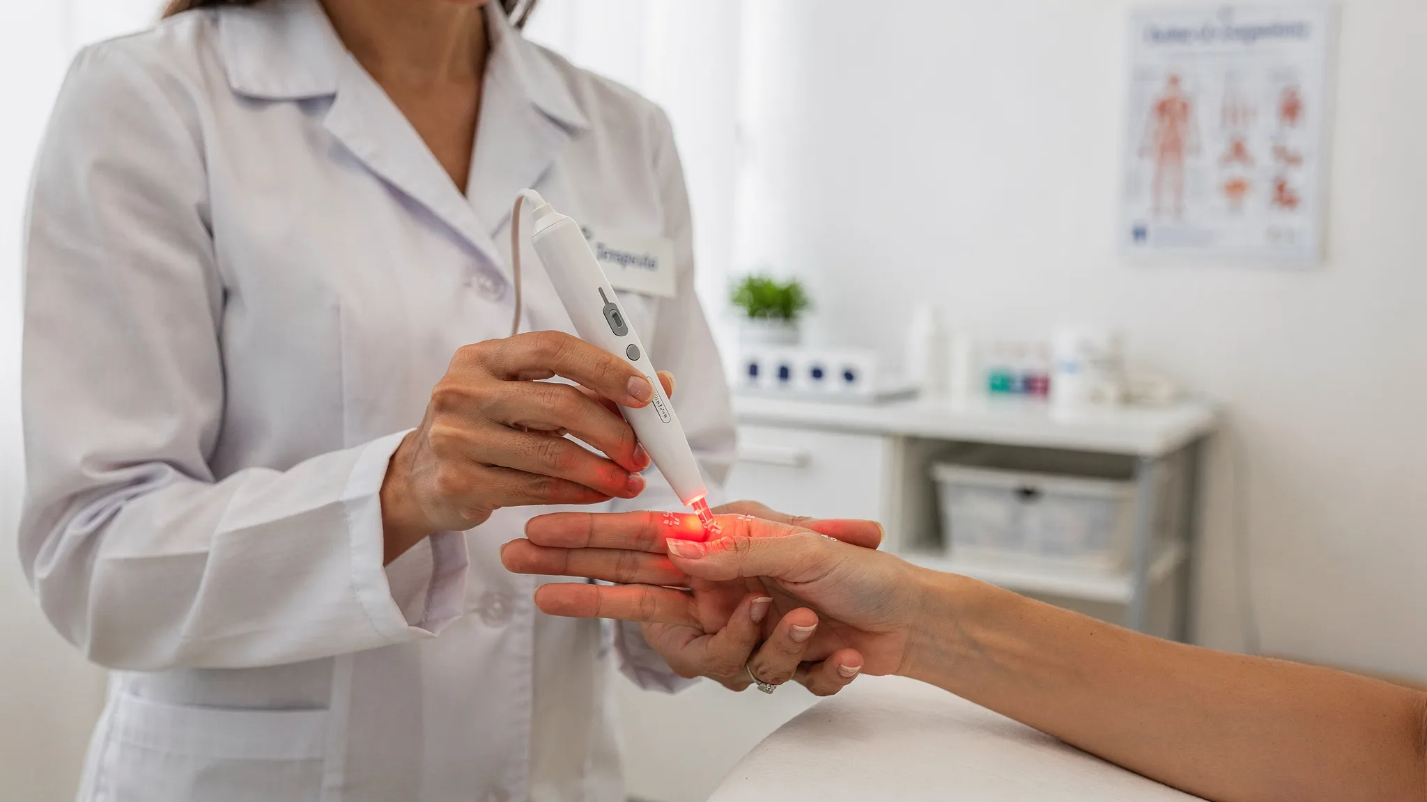 Un terapeuta aplicando acupuntura láser con un dispositivo inalámbrico de mano, sin cables visibles, apuntando a puntos de acupuntura en la mano de un paciente en una sala clínica limpia y tranquila.