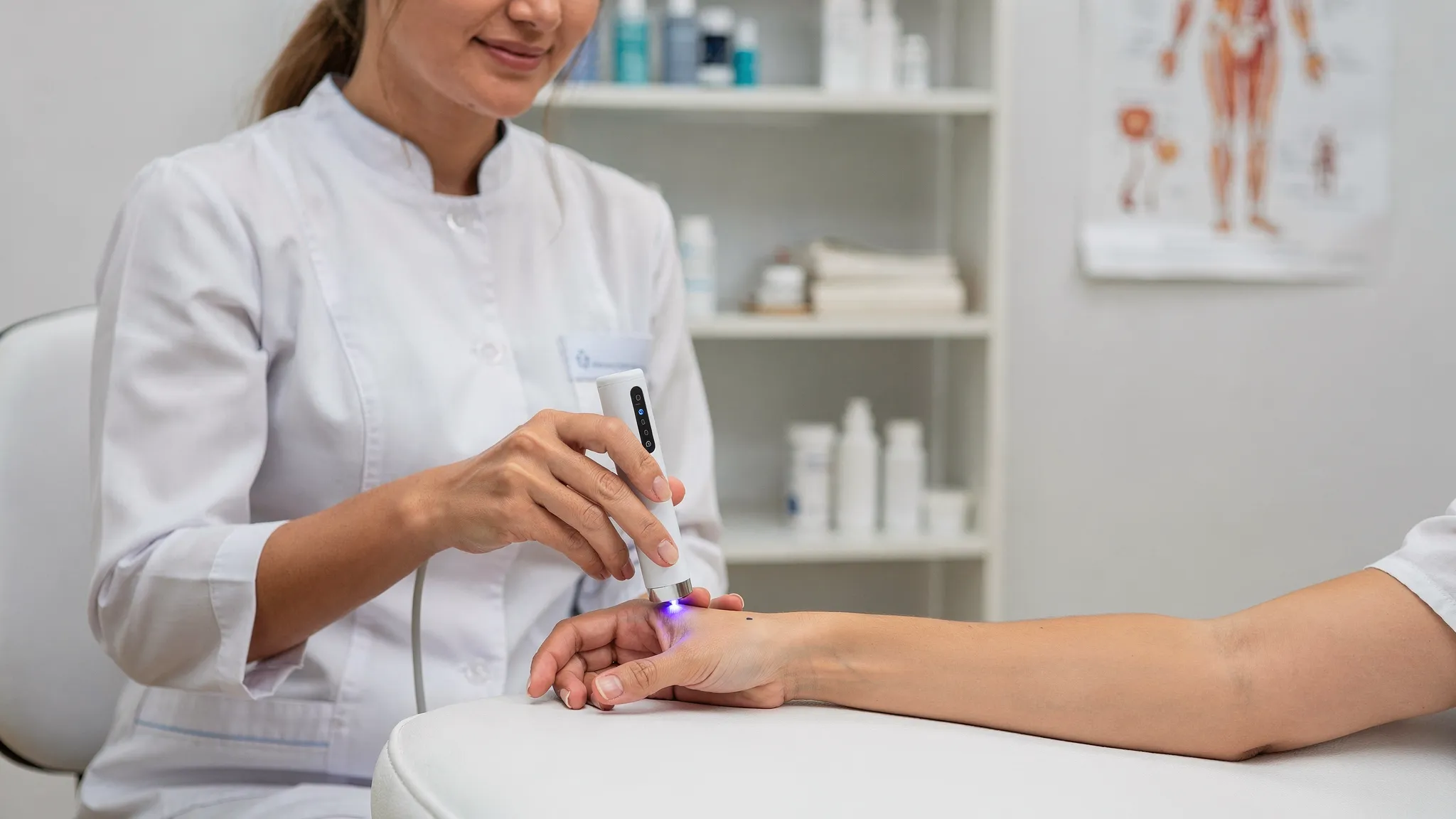 Una terapeuta aplicando acupuntura láser con un dispositivo inalámbrico de mano (sin cables), apuntando a un punto de acupuntura en la mano del paciente; ambiente de consulta clínica, sin pantallas visibles y con postura profesional.