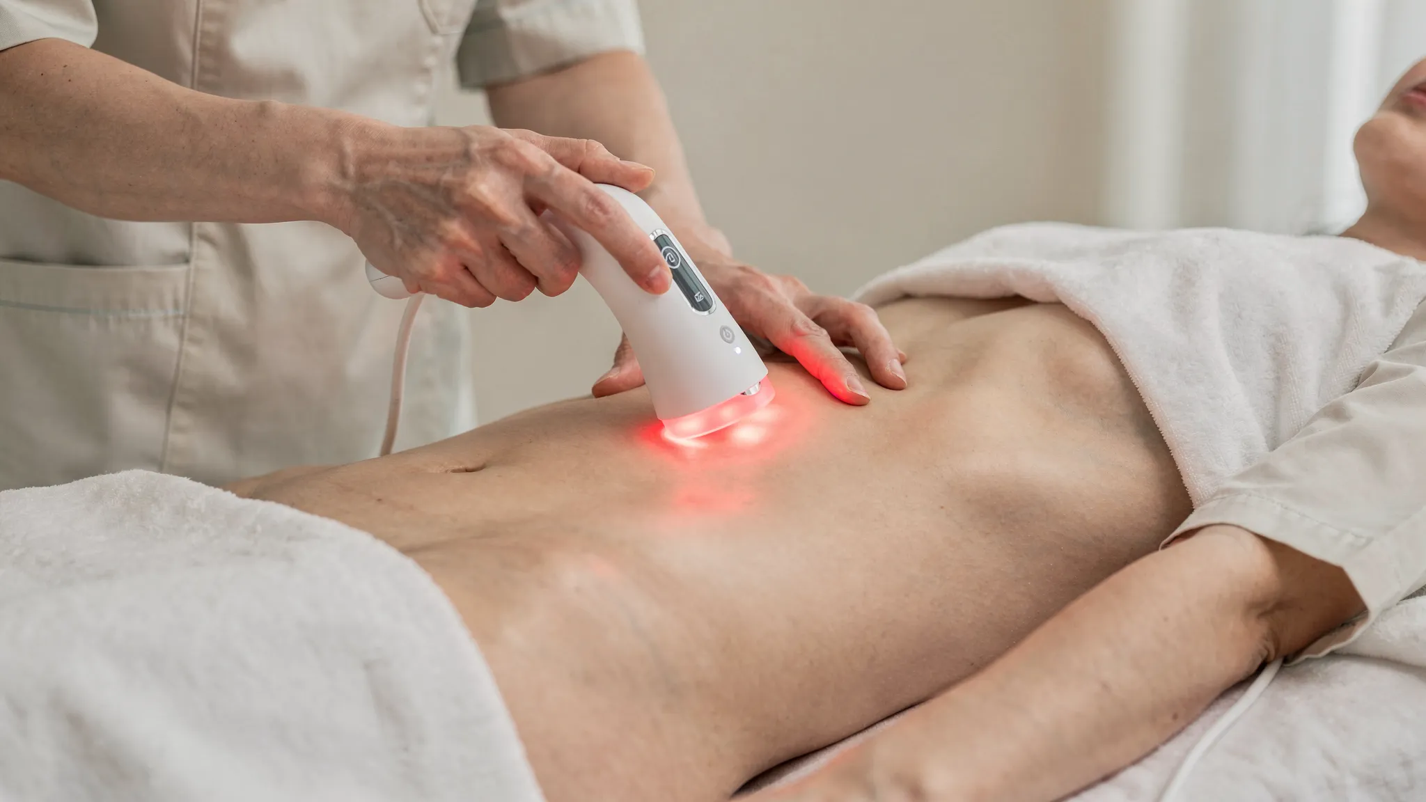 Sesión de láser-acupuntura no invasiva en abdomen y antebrazo usando un dispositivo de láser inalámbrico de mano (sin cables visibles), en un entorno clínico calmado.