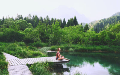 Young woman doing yoga and meditating in lotus position on the background of nature.