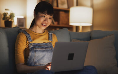 Woman using laptop computer while relaxing at home late at night