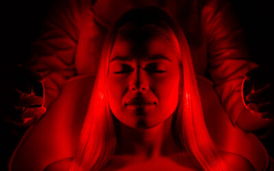 A woman undergoing skin rejuvenation with bright LED light in a modern luxurious aesthetic clinic.