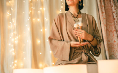 Woman holding sound healing tools in soft warm light during meditation and energy ritual