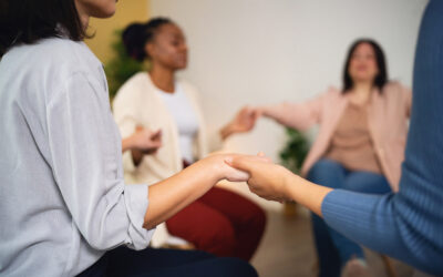 Close-up of multiracial people, in the circle holding hands, during group therapy