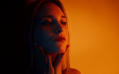 Close-up of a woman with hands on her face, blue and orange lighting