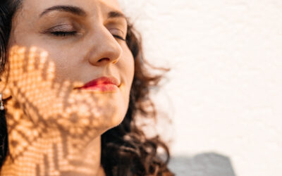 Woman with closed eyes, leaf shadow on face, enjoying sunlight, peaceful and relaxed moment