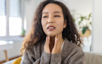 Close up of young Asian woman rubbing her inflamed tonsils, tonsilitis problem, cropped. Woman with thyroid gland problem, touching her neck, girl has a sore throat