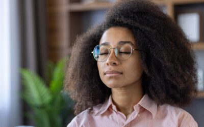 Woman with curly hair meditating indoors with eyes closed in a warm, peaceful home environment