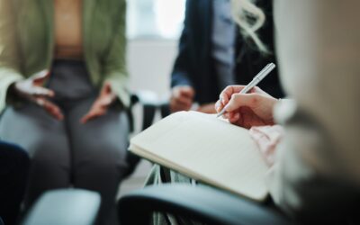 Business people, hands and writing with book in meeting for support group, therapy session or counseling. Closeup, hr or taking notes with team for company dispute or conflict resolution at workplace