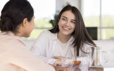 Happy diverse female friends chatting over cup of tea