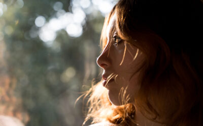 Woman standing by the window feeling the sunlight on her face