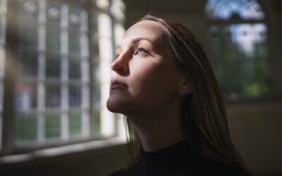 caucasian woman looking through window with face illuminated